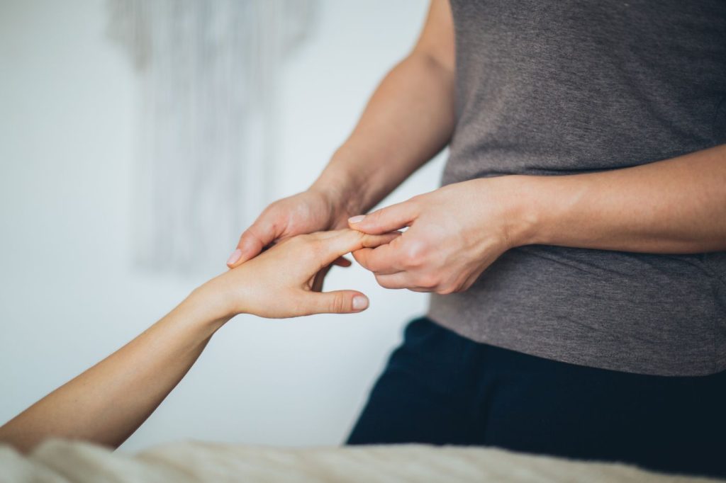 Ergotherapeutin mobilisiert die Finger einer Patientin in der Handtherapie