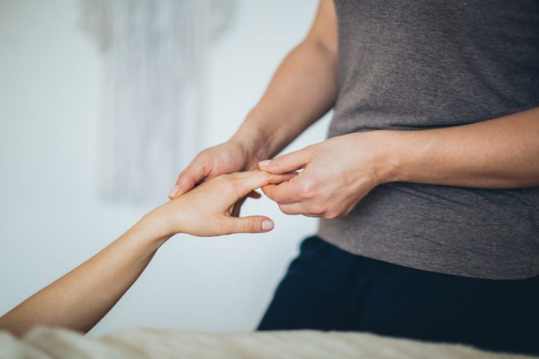 Ergotherapeutin mobilisiert die Finger einer Patientin in der Handtherapie